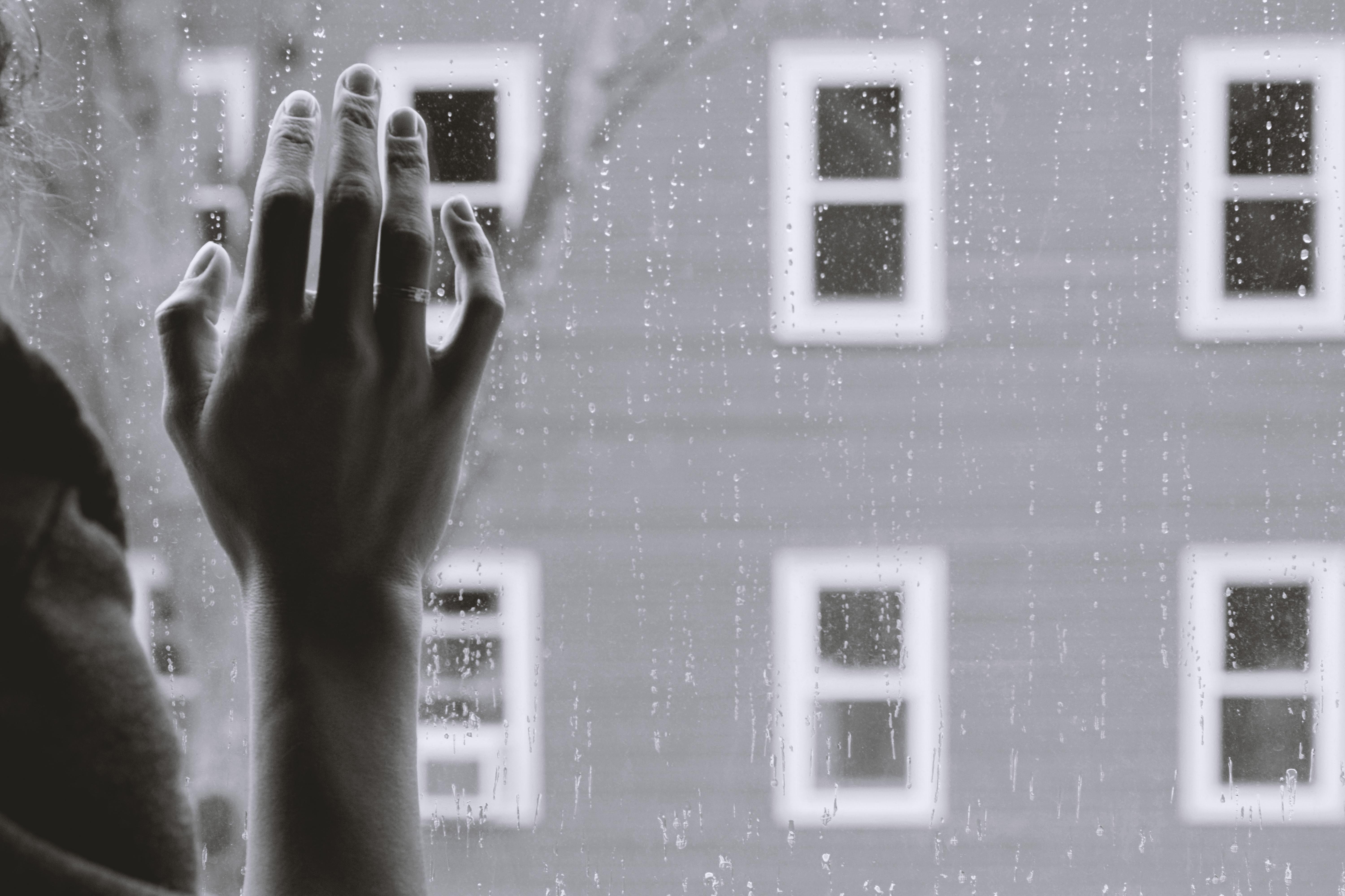black-and-white-hand-on-window-looking-out